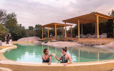 Two people enjoying cocktails in the pool at the Asilia Sayari Camp