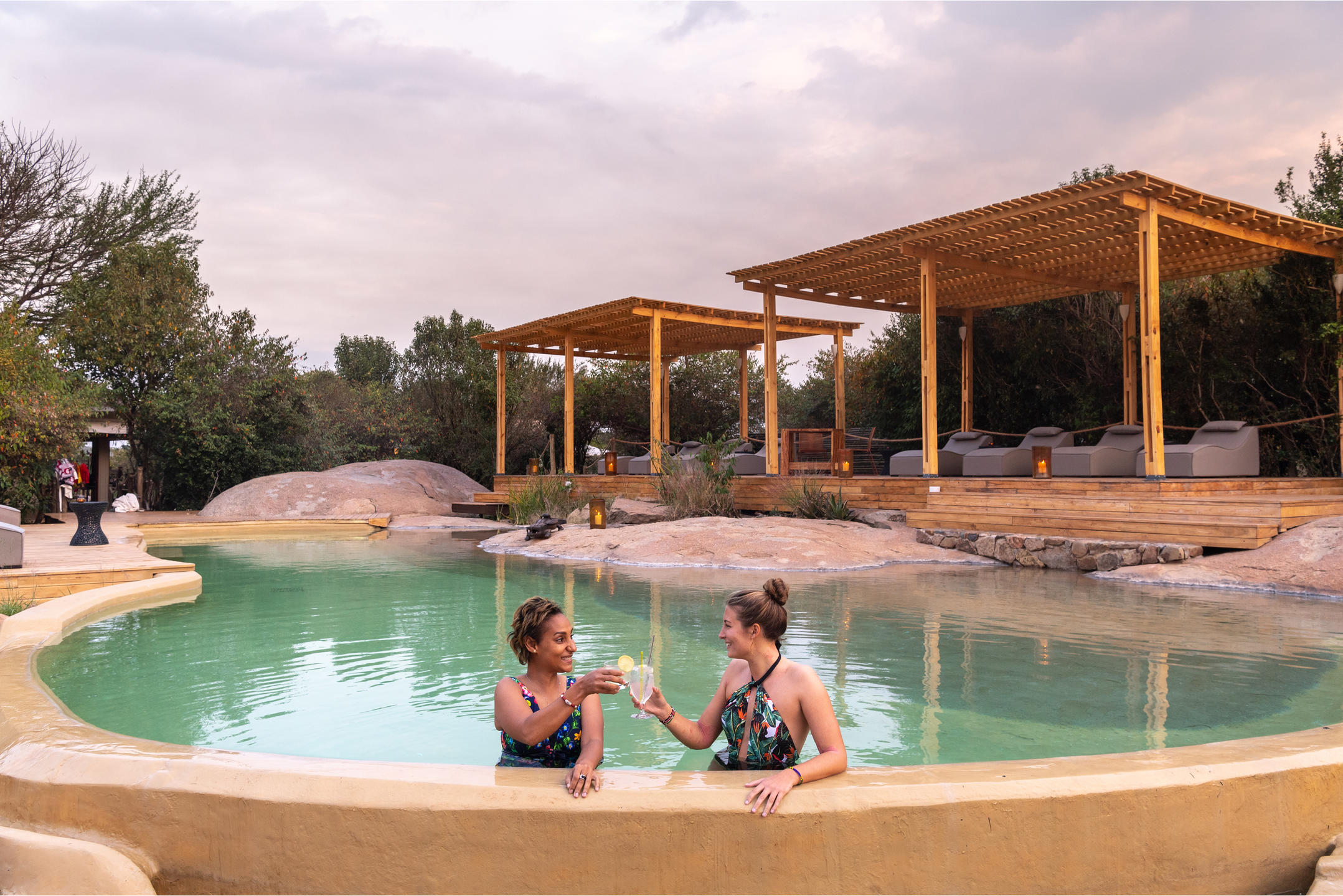 Two people enjoying cocktails in the pool at the Asilia Sayari Camp