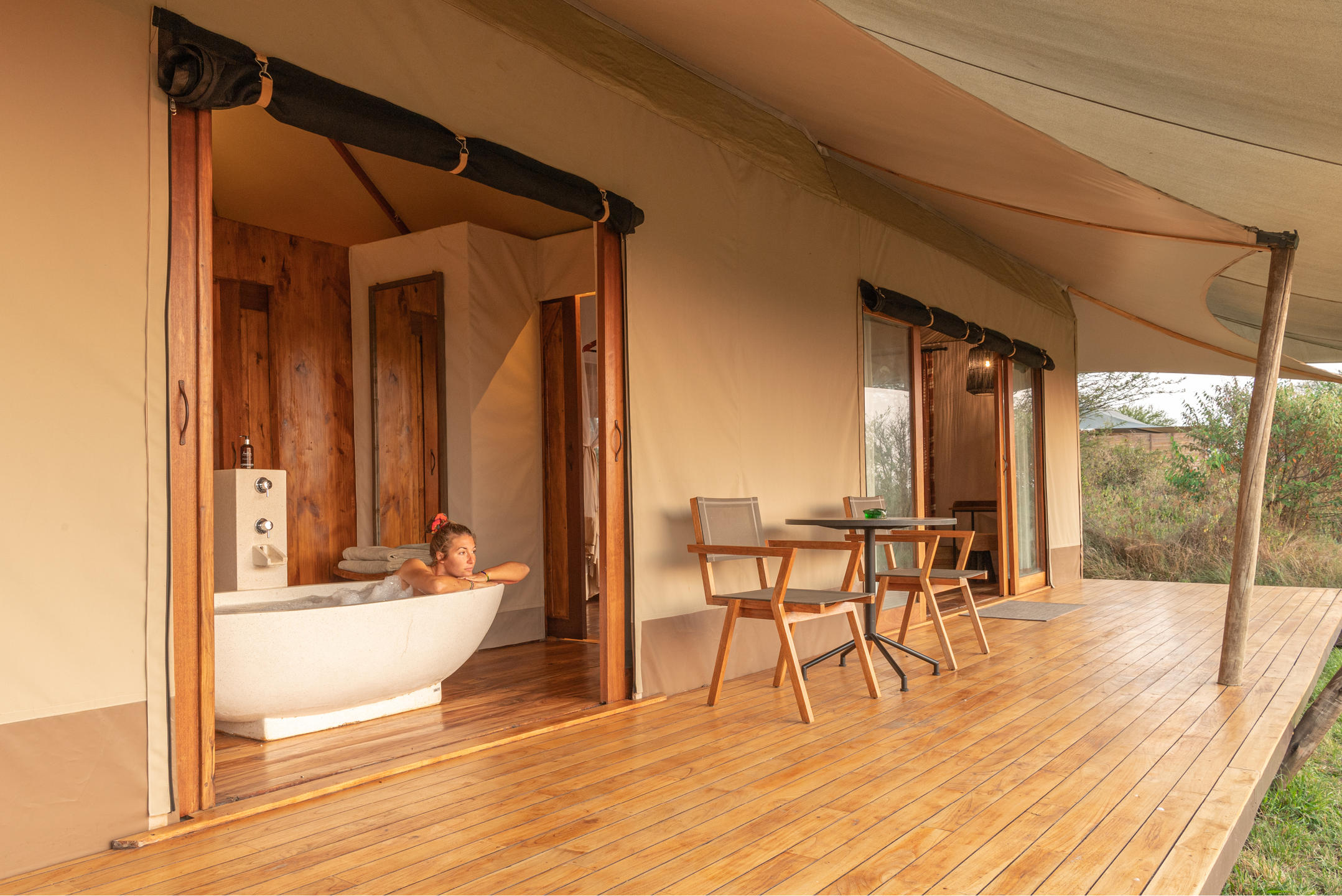 A person lounging in a luxury bathtub at the guest tent