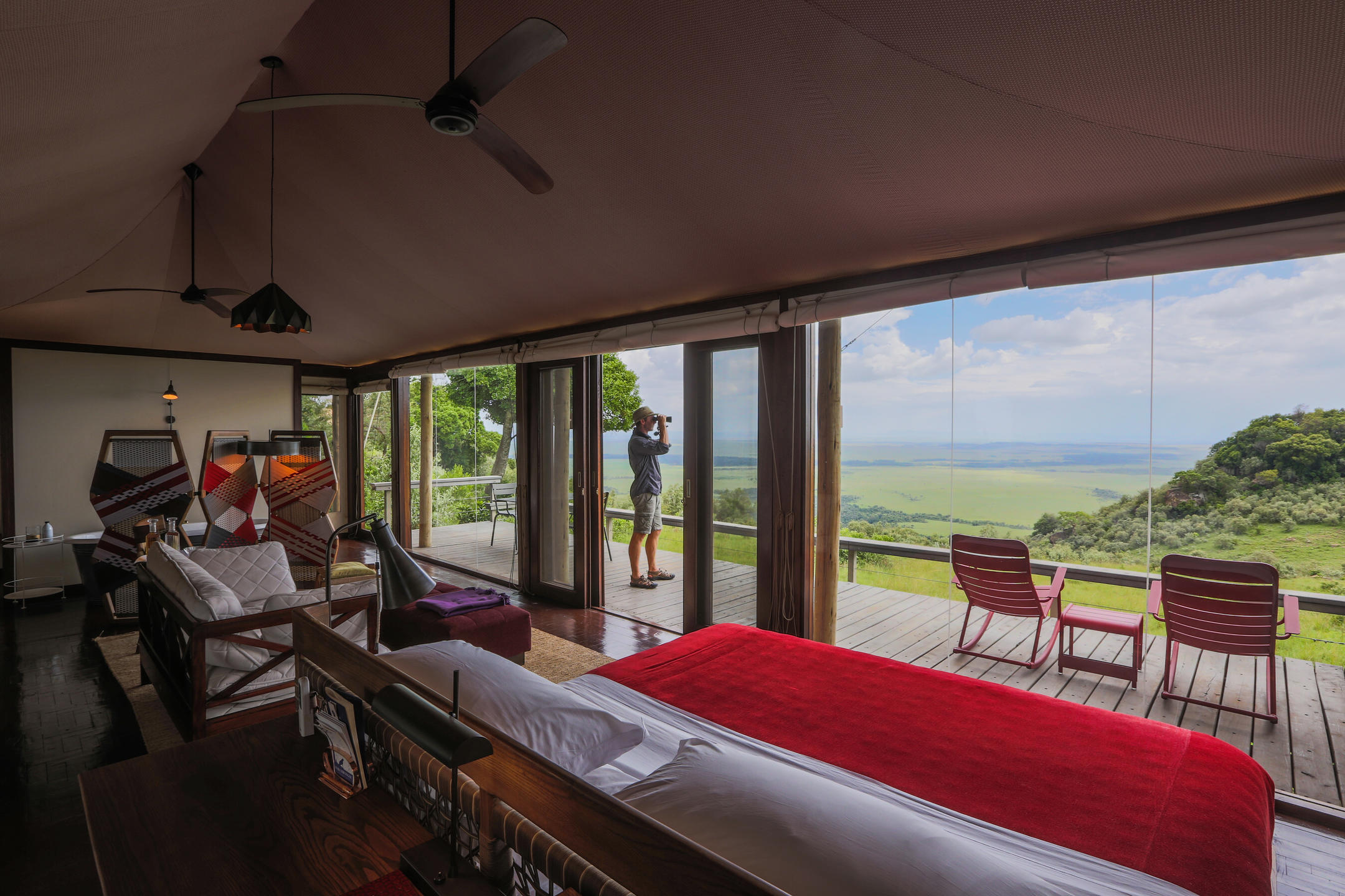 A person looking through binoculars on the deck of a suite at Angama Mara, Masai Mara, Kenya