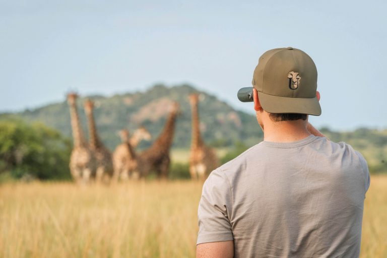 Kyle looking through binoculars at a herd of giraffe.