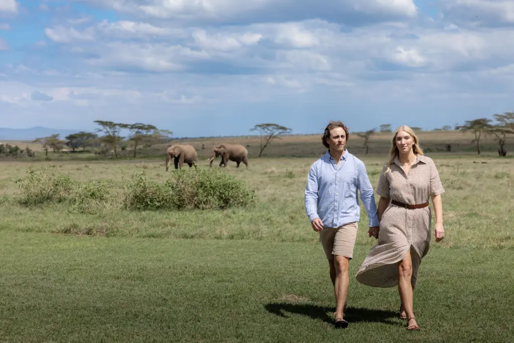 Ubuntu Travel Co-founders Kyle & Leah Green at Segera Retreat with elephants behind them. Laikipia Plateau, Kenya 